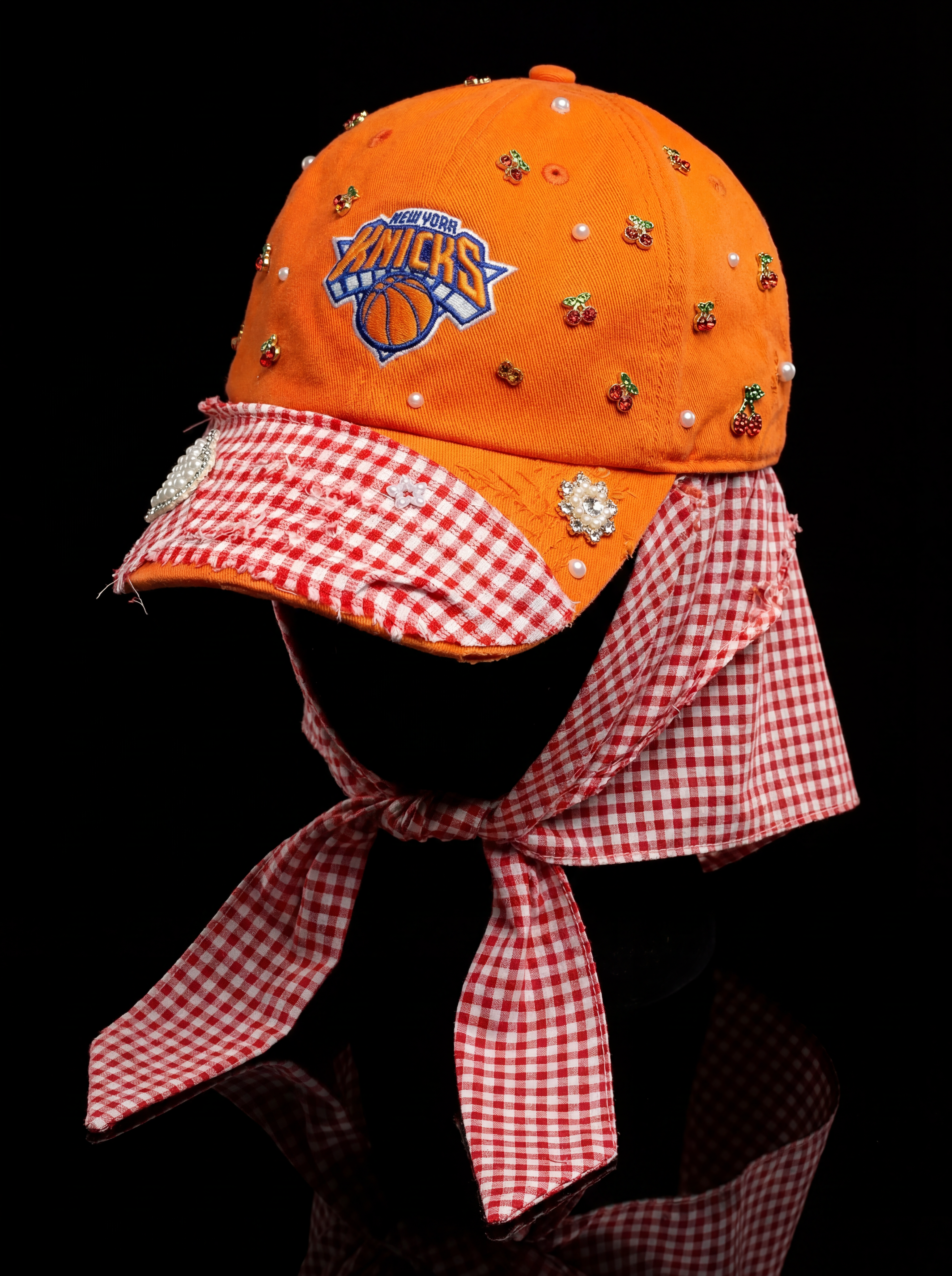Orange knicks cap with checkered scarf on a black background